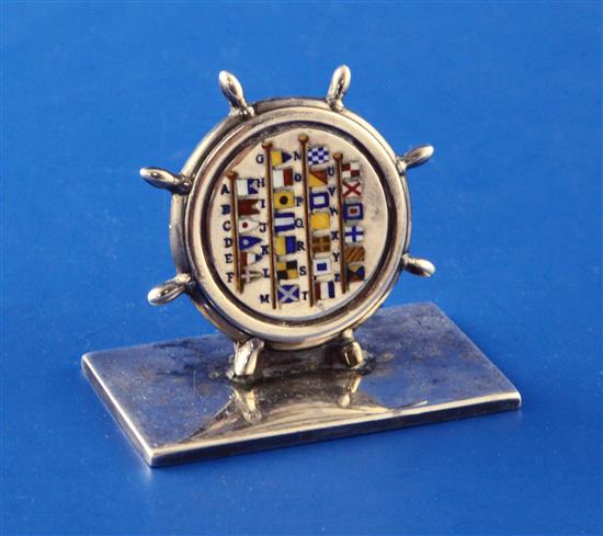 A George V silver and enamel novelty menu holder, modelled as a ships wheel enamelled with international maritime signal flags,